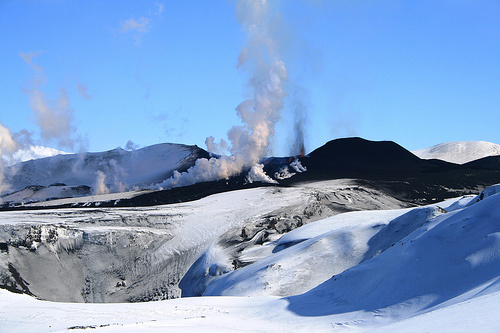 white snow, black lava, steam and ash
